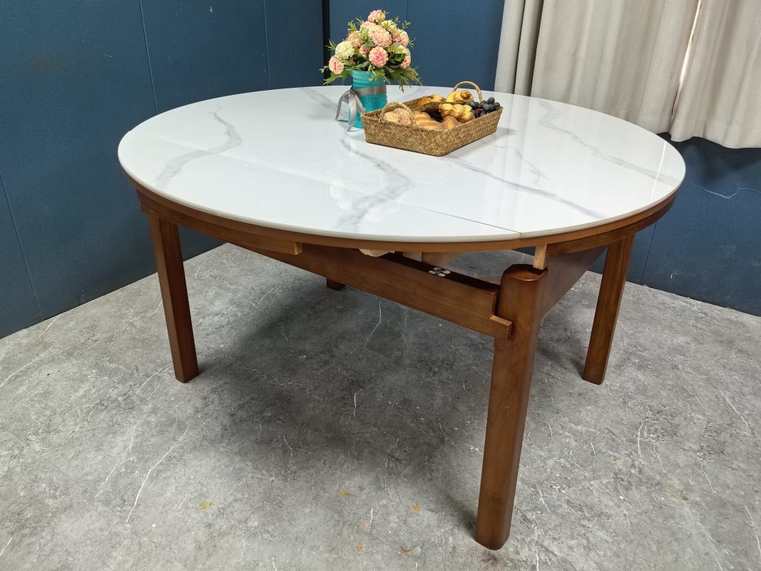 斜角全景拍攝完全展開的Camila圓形伸縮餐枱，白色岩板枱面帶灰色紋理及中央接合線，下方配胡桃色實木框架與四隻枱腳。