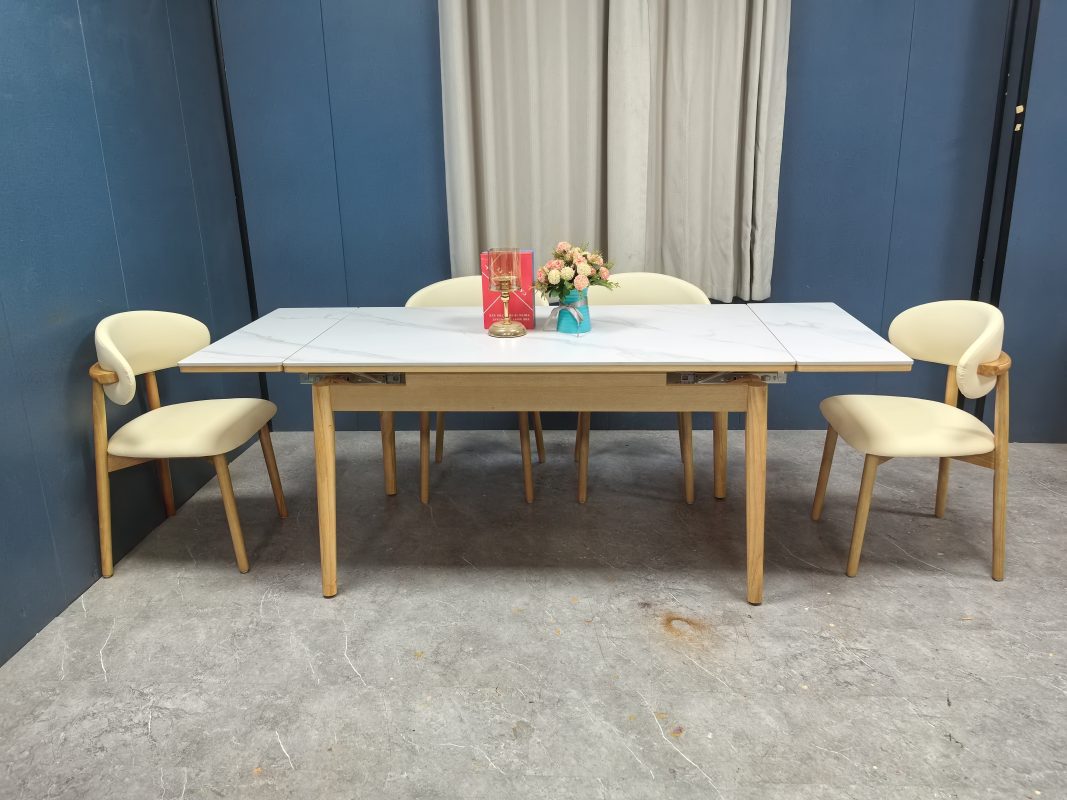 正面廣角拍攝Reese岩板伸縮餐枱完全展開狀態，左右延伸板與中央白色枱面接合，原木色枱腳前後配六張米白餐椅。