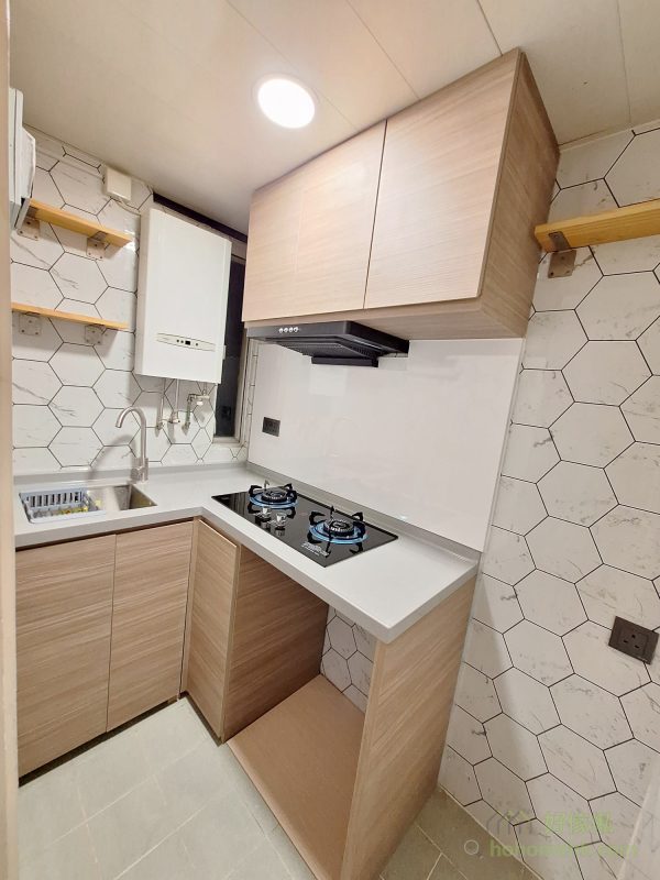 廚房傢俬採用全木紋櫃身和灰白色枱面石，與客廳的配色風格相呼應，整體感更強。廚櫃的設計簡約大方，收納空間充足，讓烹飪區域更整潔有序。而耐用的枱面石材質地堅固，易於清潔，既實用又耐看。