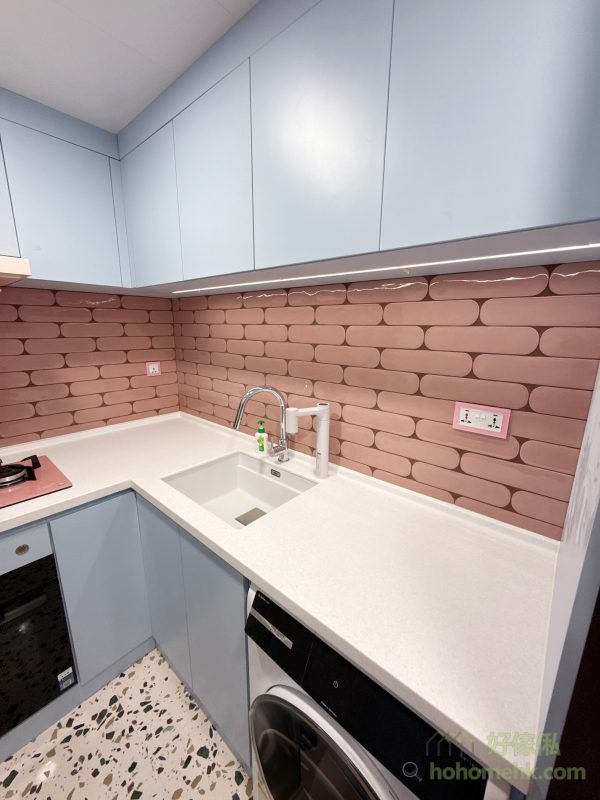 廚房的白色人造石枱面與白色鋅盤、抽油煙機融為一體，成為設計中的亮點。經過駁石師傅專業的工藝處理，枱面表層細緻光滑，連L形轉角和擋水條位置都做到完全無縫，沒有明顯駁痕。不僅易於清潔，亦展現出純粹的設計美感，全方位滿足客戶對細節的高要求。