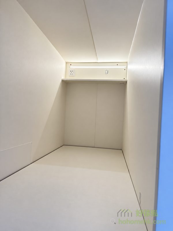 由床尾望入白色工人床櫃內籠，床頭設一字窄層板、白色插座及小型掣位，層板下方燈帶亮起，照亮淺色床台與兩側牆身。